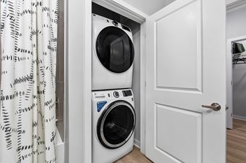 A white washing machine is in a small white closet.